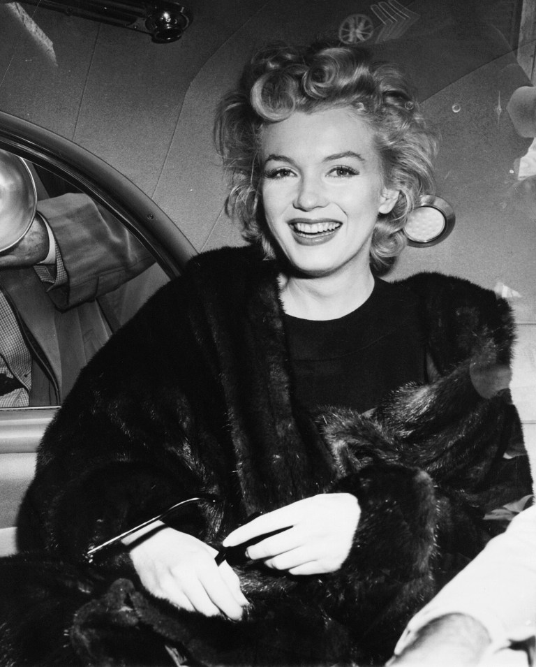   FILE - In this June 2, unknown year, file photo, actress Marilyn Monroe smiles in a car after arriving tousled from an all-night plane flight from Hollywood to Idlewild Airport, in New York. The actress said she planned to rest in New York before going to England to make a new movie with Sir Laurence Olivier. In late 2012, the FBI has released a new version of files it kept on Monroe that reveal the names of some of her acquaintances who had drawn concern from government officials and members of her entourage over their suspected ties to communism. (AP Photo, File)  