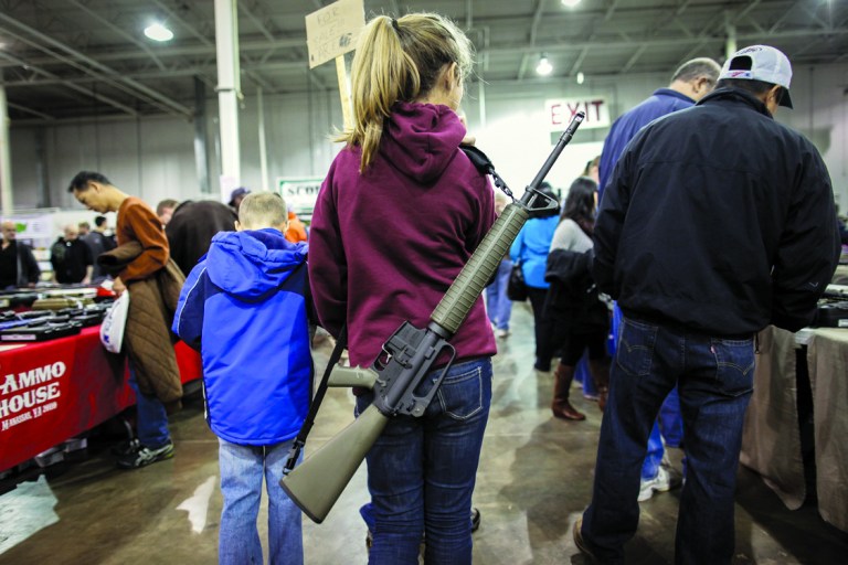A young girl with a rifle slung over her shoulder at a gun show in Chantilly, VA, Saturday, December 29th, 2012