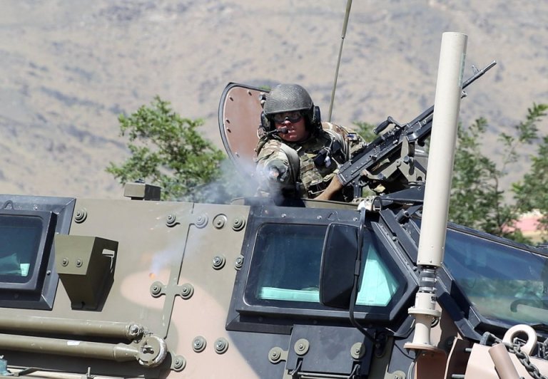 A NATO soldier opens fire toward journalists near the main gate of Camp Qargha, west of Kabul, Afghanistan, Tuesday, Aug. 5, 2014. A man dressed in an Afghan army uniform opened fire Tuesday on foreign troops at a military base, causing casualties, an Afghan military spokesman said. (AP Photo/Massoud Hossaini)