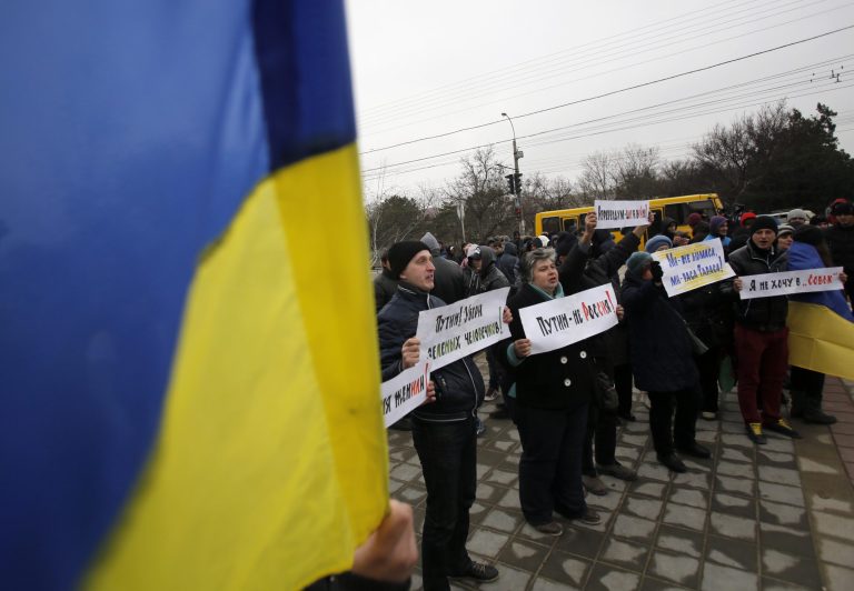 People hold Ukrainian flags and banners that read: 
