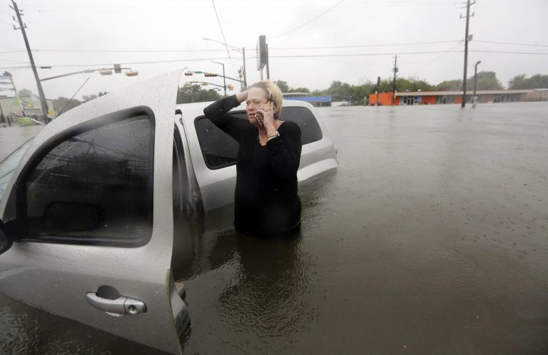 Rhonda Worthington talks on her cell phone with a 911 dispatcher after her car become stuck in rising floodwaters from Tropical Storm Harvey in Houston, Texas, Monday, on Aug. 28. In the coming weeks, the government is expected to finalize its estimate of how much federal aid states and territories will need to update their 911 services. (AP Photo/LM Otero)