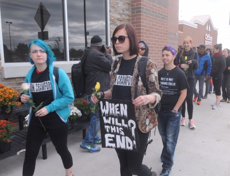 FILE - In this Sept. 22, 2014 file photo, demonstrators walk in front of the Beavercreek, Ohio, Wal-Mart, where customer John Crawford III was shot and killed by police Aug. 5. The family of Crawford says soundless surveillance video shows their actions were unreasonable. But a prosecutor cited the same video to explain the shooting was justified. (AP Photo/The Dayton Daily News, Marshall Gorby, File)  LOCAL PRINT OUT; LOCAL TELEVISION OUT; WKEF-TV OUT; WRGT-TV OUT; WDTN-TV OUT