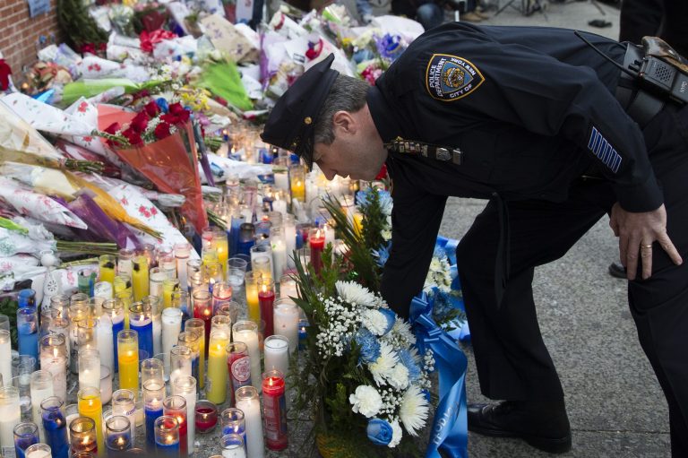Patrick Lynch, president of the Patrolman's Benevolent Association, places flowers at a makeshift memorial, on Monday, Dec. 22, 2014, near the site where New York Police Department officers Rafael Ramos and Wenjian Liu were murdered in the Brooklyn borough of New York. Police say Ismaaiyl Brinsley ambushed the two officers in their patrol car in broad daylight Saturday, fatally shooting them before killing himself inside a subway station. (AP Photo/John Minchillo)