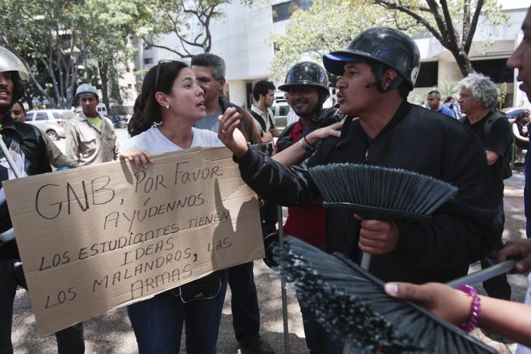 A anti-government demonstrator, left, argues with a pro-government supporter inside of Plaza Altamira in Caracas, Venezuela, Monday, March 17, 2014. The cardboard sign the woman carries reads ins Spanish 