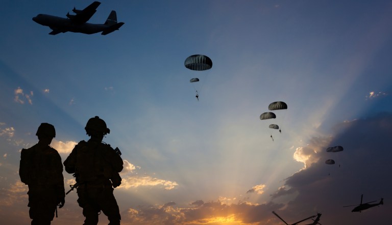 ATTENTION FOR INSPECTOR: This is a composite photo and the date of model releases are different from the date of image. Please consider this. Paratroopers jumping from the plane and military helicopters leave behind soldiers for a night mission.