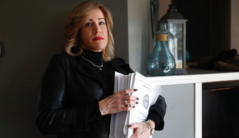 In this Tuesday, Jan. 7, 2020, photo, Amy Braley Franck, a civilian victim advocate with the 416th Theater Engineer Command, poses for a portrait with more than 800 pages from several sexual abuse reports at her home in Oswego, Ill.
