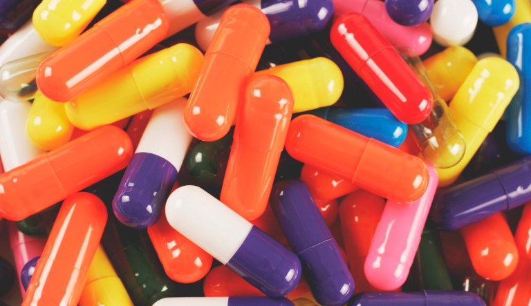 Medicinal drug capsules of various vibrant colors are shown.
