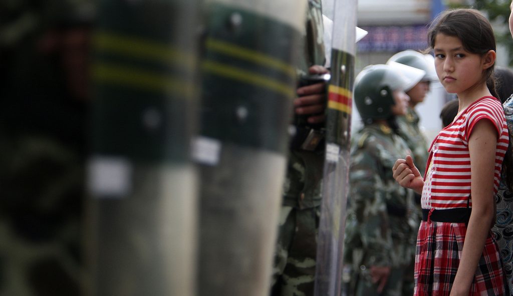 A Uyghur girl is stopped by a line of riot police officers as she watches the parade of paramilitary police officers in Urumqi, western China's Xinjiang province, Thursday, July 9, 2009.