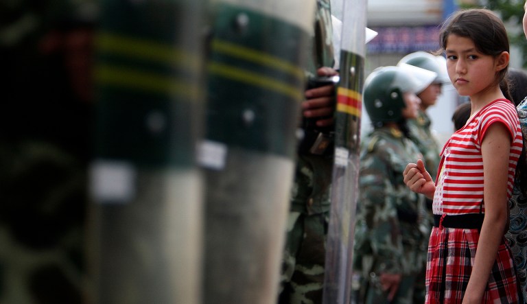 A Uyghur girl is stopped by a line of riot police officers as she watches the parade of paramilitary police officers in Urumqi, western China's Xinjiang province, Thursday, July 9, 2009.
