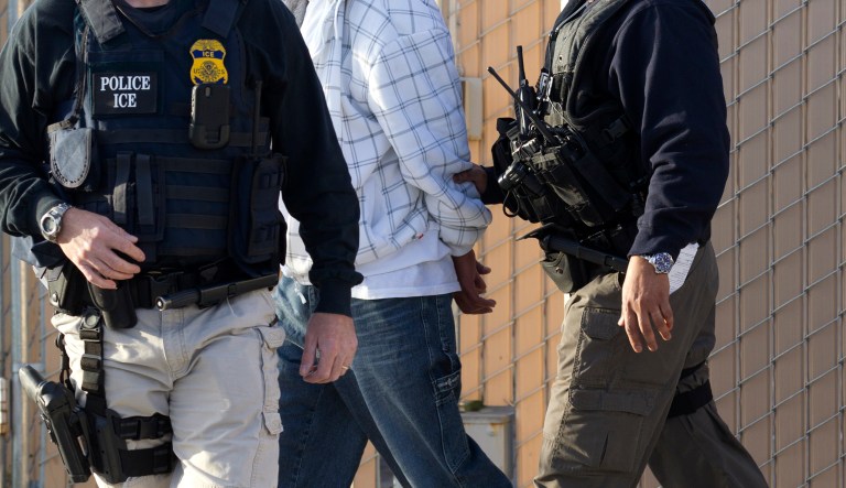 Immigration and Customs Enforcement (ICE) agents take a suspect into custody as part of a nationwide immigration sweep. 