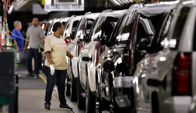 An auto worker inspects finished SUVs coming off the assembly line at the General Motors auto plant in Arlington, Texas.