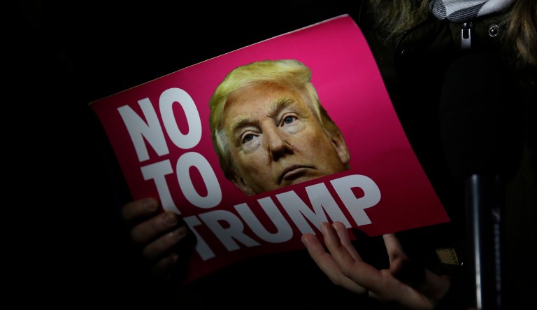 A woman holds a placard as she gives a television interview during an anti-racism protest against President-elect Donald Trump winning the American election, outside the U.S. embassy in London, Wednesday, Nov. 9, 2016. 