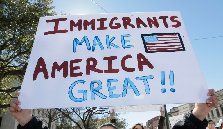A protest sign saying "Immigrants Make America Great" is seen in Texas.