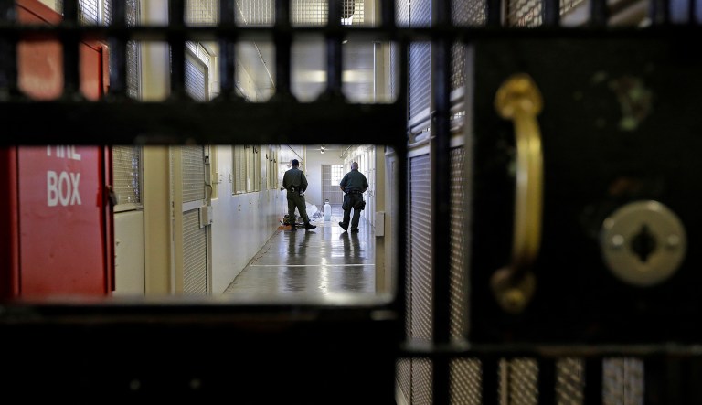 Guards walk down the corridor of a prison cell.