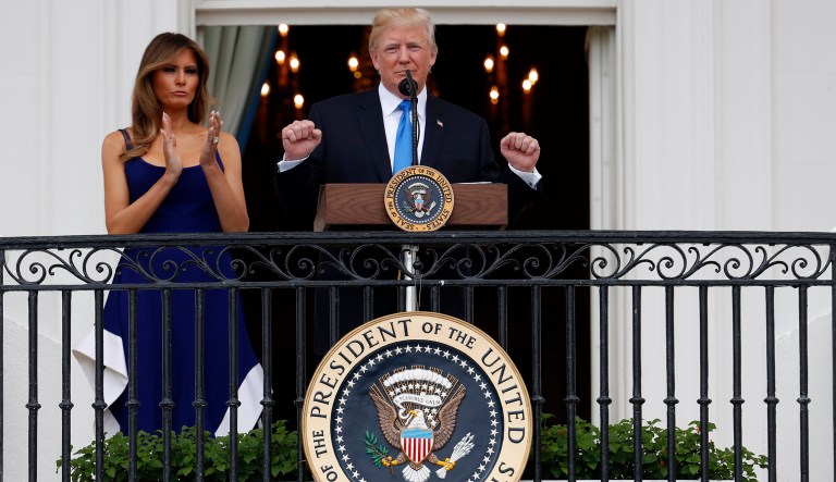 President Donald Trump, with first lady Melania Trump, gestures while speaking from the Truman Balcony at the Fourth of July picnic for military families on the South Lawn of the White House, Tuesday, July 4, 2017, in Washington. 