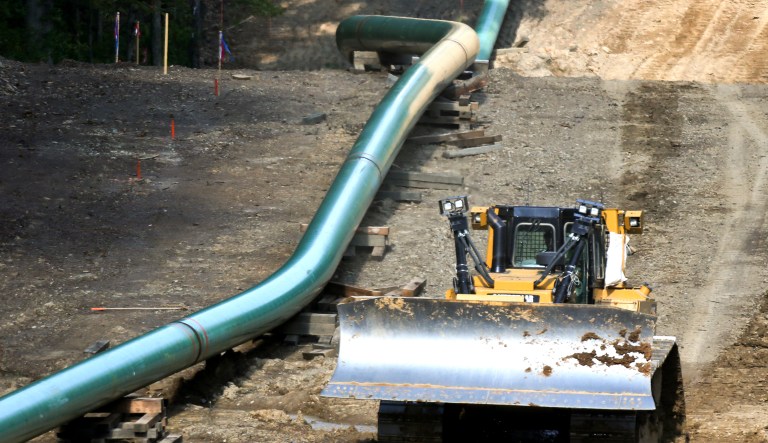 An operator moves a bulldozer along a section of assembled pipe lined up along a cleared section of woods where a pipeline for shale gas is under construction in Jackson Township, Pa.