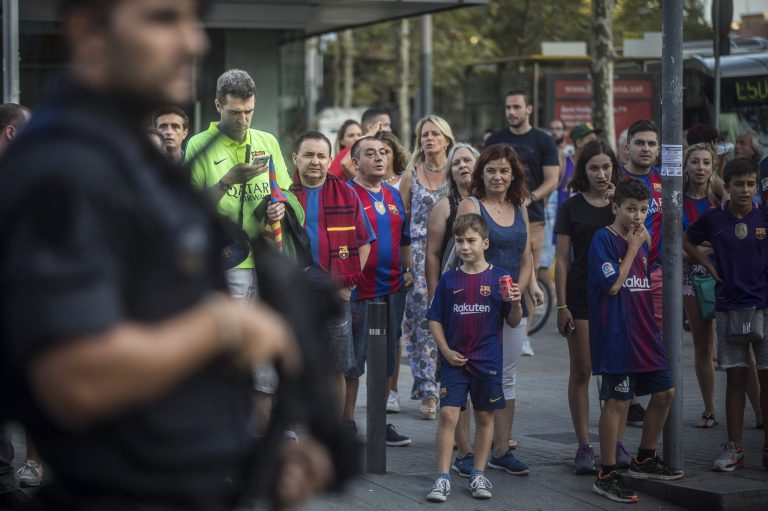 Fans look at an armed police officer near the stadium before a La Liga soccer match between Barcelona and Betis at the Camp Nou stadium in Barcelona , Spain, Sunday, Aug. 20, 2017. Security was stepped up for the match after a terror attack that killed 14 people and wounded over 120 in Barcelona and police put up scores of roadblocks across northeast Spain on Sunday in hopes of capturing a fugitive suspect at large following the vehicle attack.