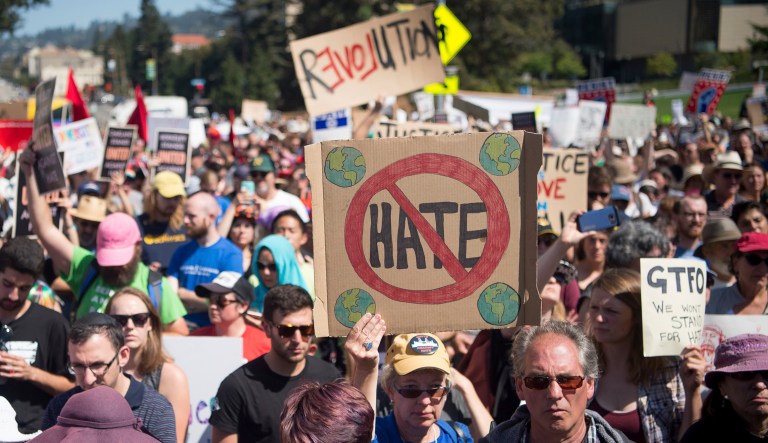 People hold up signs during a rally against hate speech. 