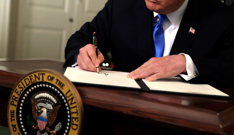 President Trump signs something in the White House.