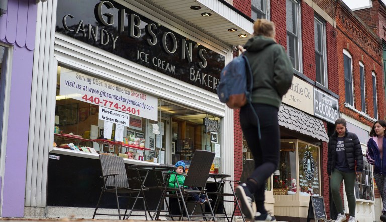 In this Nov. 22, 2017 photo, pedestrians pass the storefront of Gibson's Food Mart & Bakery in Oberlin, Ohio. A long relationship between one of Americas most liberal colleges and 132-year-old family-owned Gibson's is in tatters amid student allegations of racial profiling. The bakery filed a lawsuit last month accusing the college and a top dean of slandering Gibson's as a racist establishment and taking steps to destroy the family's livelihood.