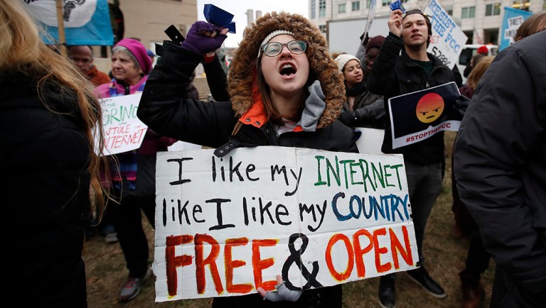 A protester holds a sign that reads "I like My Internet Like I Like my Country Free & Open" as she protests the FCC.
