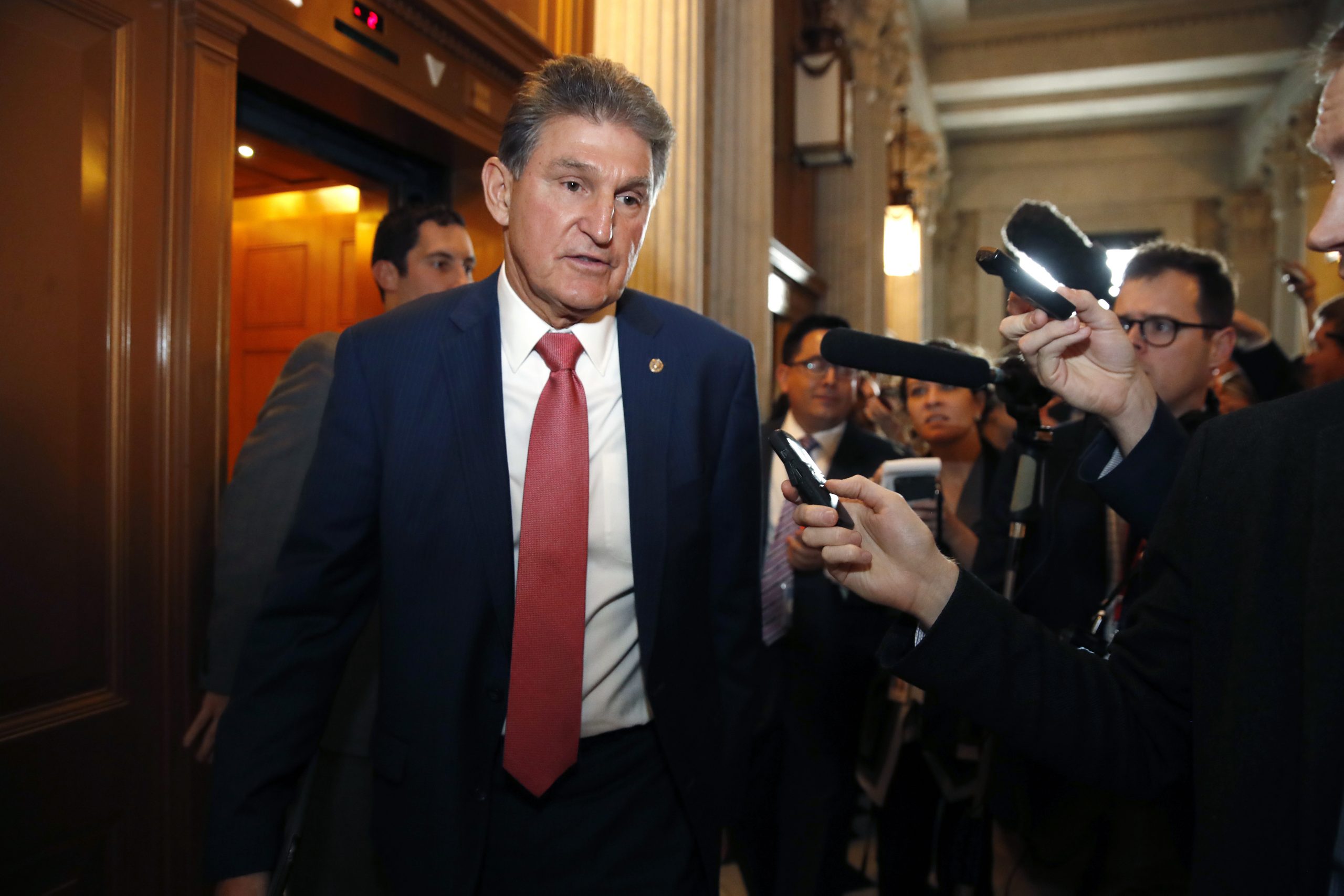Sen. Joe Manchin, D-W.Va., left, walks past reporters as he heads to the Senate.