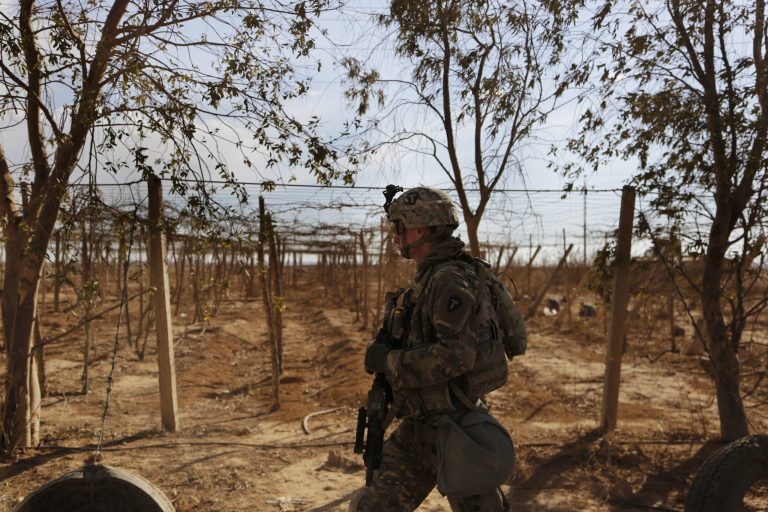 In this Jan. 27 photo, a U.S. Army soldier walks through fields and passes by orchards while on a reconnaissance patrol in a rural village near a coalition outpost in western Iraq.