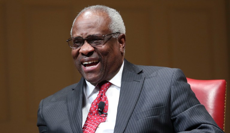 Supreme Court Associate Justice Clarence Thomas smiles as he is introduced during an event.