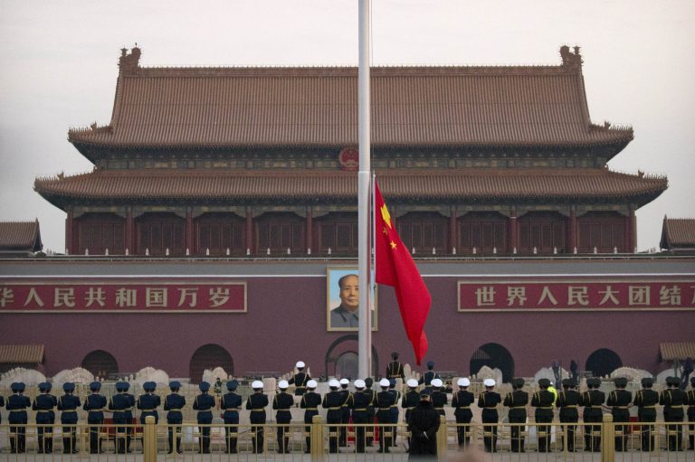 A Chinese honor guard raises the national flag of China at dawn on Tiananmen Square in Beijing.