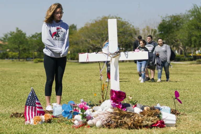 Gabrielle Glorioso, from Monarch High School, looks at a makeshift memorial, after she walked out of school and made her way to Pine Trails Park in Parkland, Fla., on Wednesday, March 14, 2018.