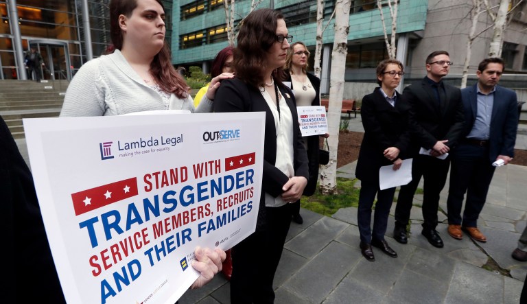 Plaintiffs Cathrine Schmid, second left, and Conner Callahan, second right, listens with supporters during a news conference in front of a federal courthouse following a hearing there in Seattle. U.S. District Judge Marsha Pechman says she won't immediately consider President Trump's new policy banning transgender people from serving in the military. 