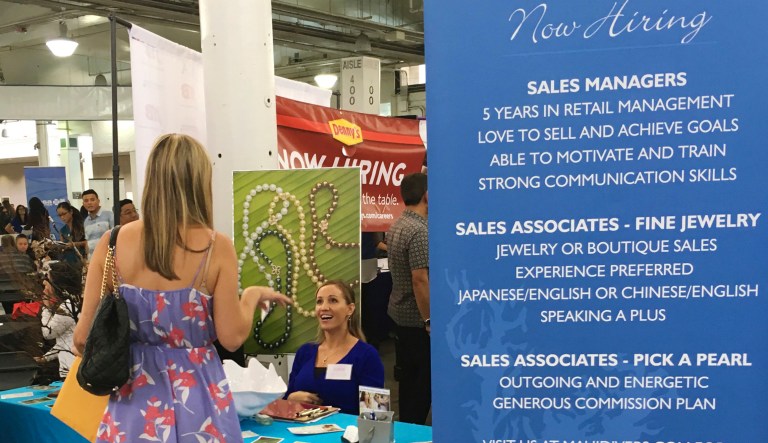 A woman speaks to Maui Divers Jewelry representatives at a job fair in Honolulu. Recently released numbers show Hawaii boasts the United States' lowest jobless rate. 