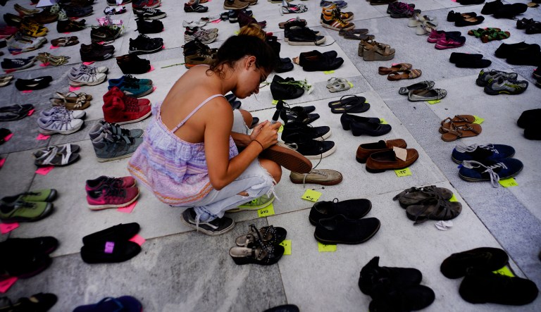 A woman places one of the hundreds of shoes in memory of those killed by Hurricane Maria in front of the Puerto Rico Capitol, in San Juan.