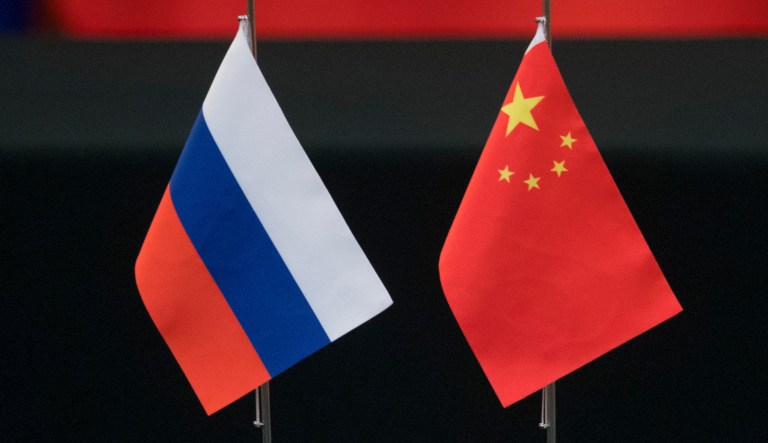 Russian and Chinese flags sit on a table. 