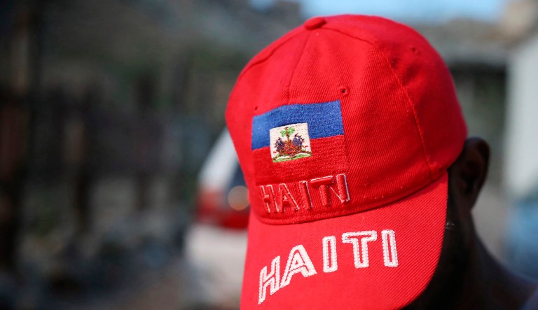 A Haitian migrant shows off a red cap with his country's flag emblazoned on it.