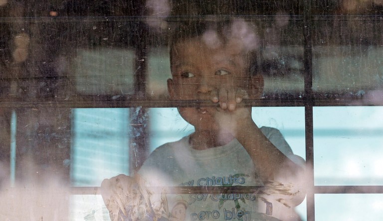 An immigrant child looks out from a U.S. Border Patrol bus leaving as protesters block the street outside the U.S. Border Patrol Central Processing Center Saturday, June 23, 2018, in McAllen, Texas. Additional law enforcement officials were called in to help control the crowd and allow the bus to move.