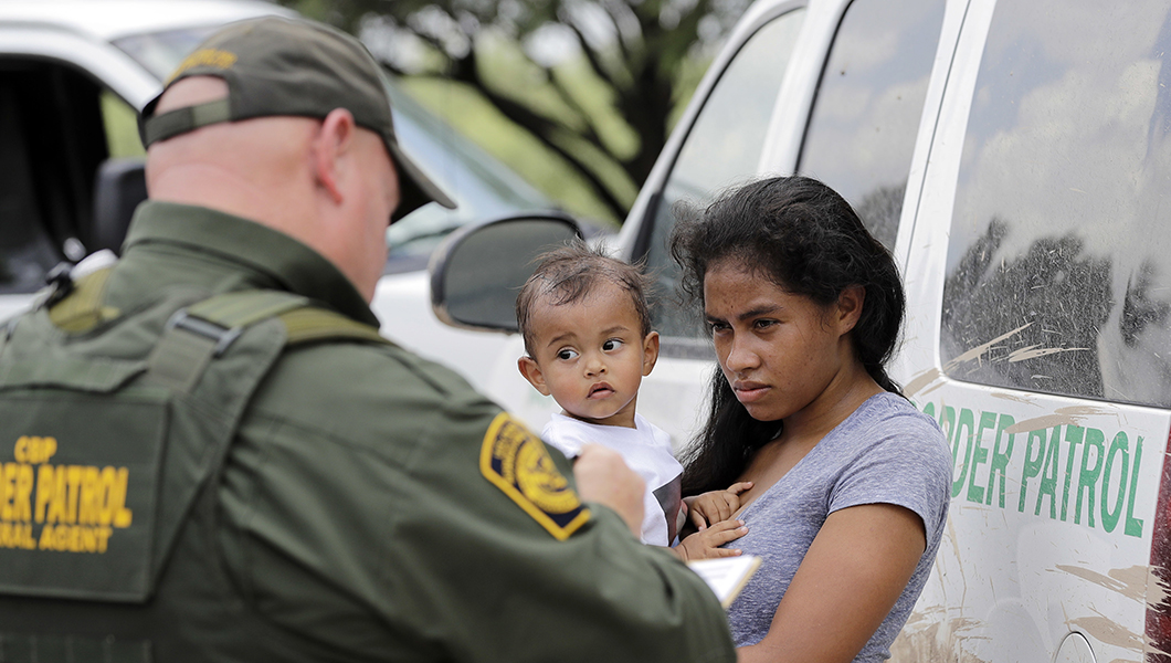 A mother migrating from Honduras holds her 1-year-old child as surrendering to U.S. Border Patrol agents after illegally crossing the border.