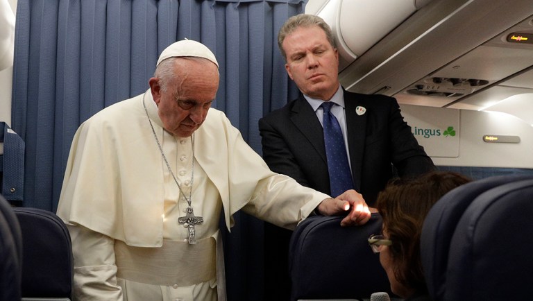 Pope Francis, flanked by Vatican spokesperson Greg Burke, listens to a journalist's question during a press conference aboard of the flight to Rome at the end of his two-day visit to Ireland.