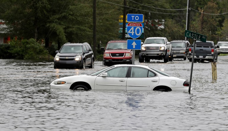 Cars try to navigate a flooded road leading to Interstate 40 in Castle Hayne, N.C., after damage from Hurricane Florence cut off access to Wilmington, N.C., Sunday, Sept. 16, 2018. 