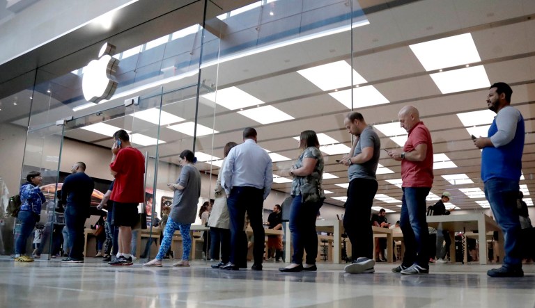 People wait in line outside of an Apple store.