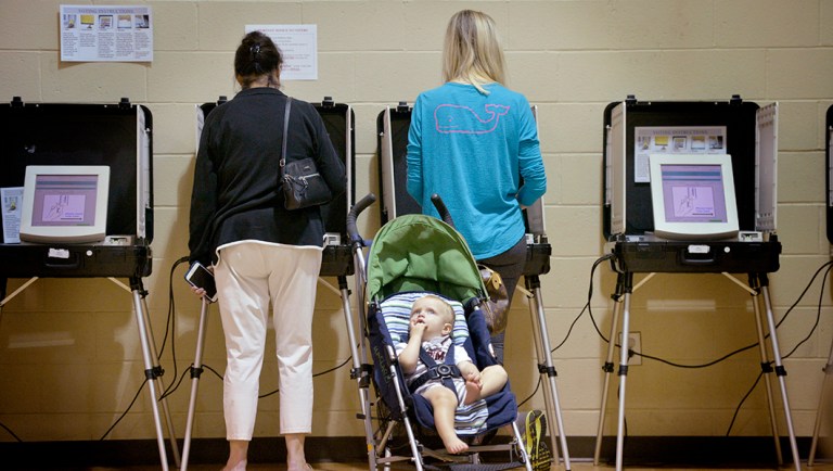 Nolan Lakvold, 17 months, waits for his mother, Kathryn Lakvold, right, to finish voting on Election Day in Augusta, Ga.