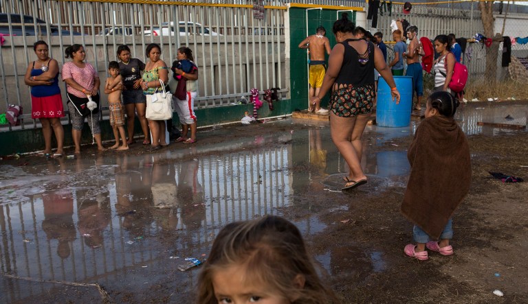 Central American migrants have a bath at a temporary shelter, near barriers that separate Mexico and the United States, in Tijuana, Mexico, Wednesday, Nov. 21, 2018. Migrants camped in Tijuana after traveling in a caravan to reach the U.S are weighing their options after a U.S. court blocked President Donald Trump's asylum ban for illegal border crossers. 