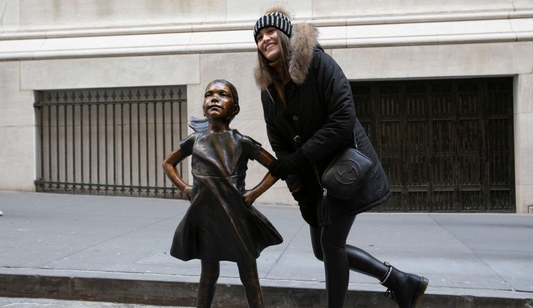 A woman poses with the "Fearless Girl" statue after it is unveiled at its new location in front of the New York Stock Exchange, Monday, Dec. 10, 2018, in New York. 