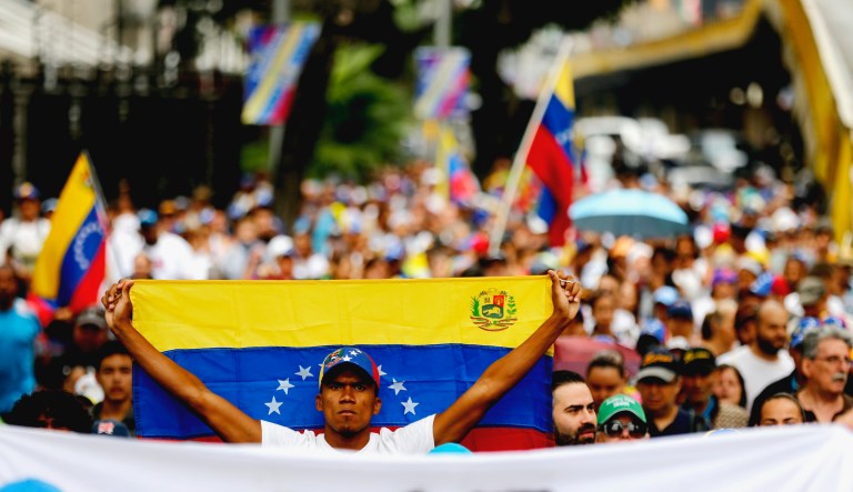 An opposition member holds a Venezuelan national flag during a protest march against President Nicolas Maduro in Caracas, Venezuela.
