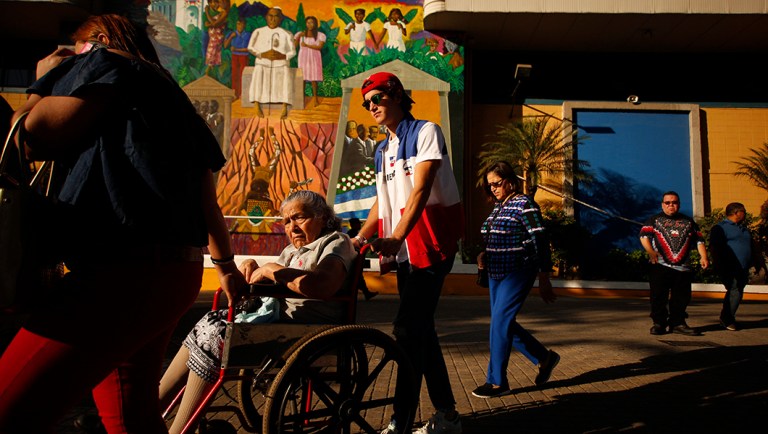 An election volunteer helps a woman in a wheelchair reach her voting table during the presidential election in San Salvador, El Salvador.