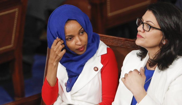 In this Feb. 5, 2019 photo, Rep. Ilhan Omar, D-Minn., left, joined at right by Rep. Rashida Tlaib, D-Mich., listens to President Donald Trump's State of the Union speech, at the Capitol in Washington. 
