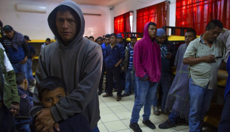 In this Feb. 26, 2019 photo, Carlos, 34, holds his son Carlos, 7, as they wait to get breakfast at the San Juan Bosco migrant shelter, in Nogales, Mexico. 