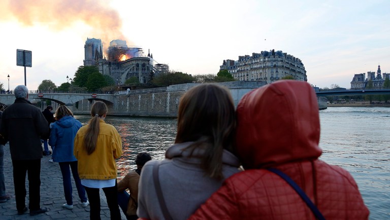 People watch as flames and smoke rise from Notre Dame cathedral as it burns in Paris.
