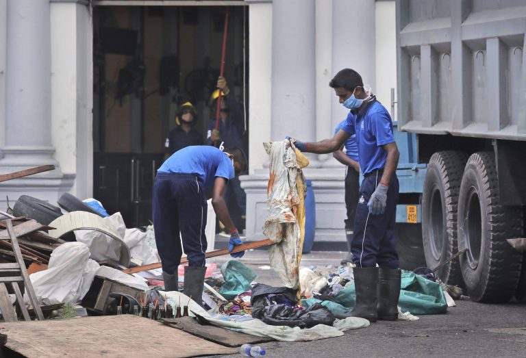 Sri Lankan naval soldiers check a blood soaked cloth as others clear the debris from inside of the damaged St. Anthony's Church.