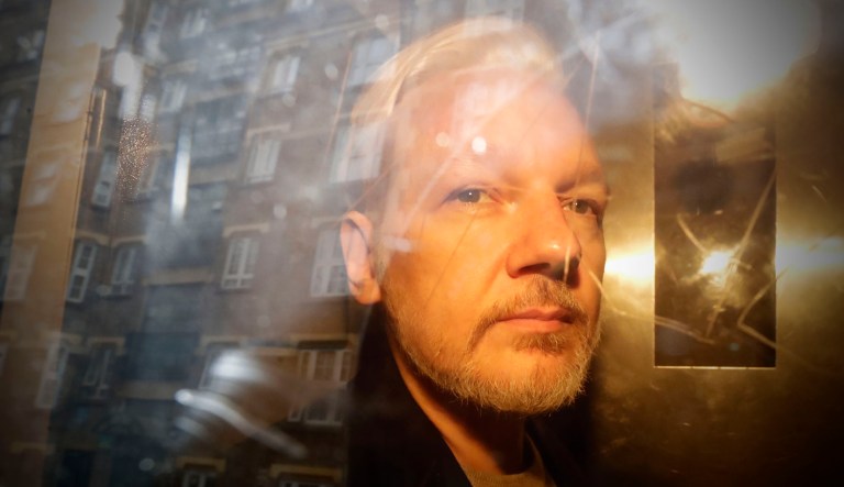 Buildings are reflected in the window as WikiLeaks founder Julian Assange is taken from court.